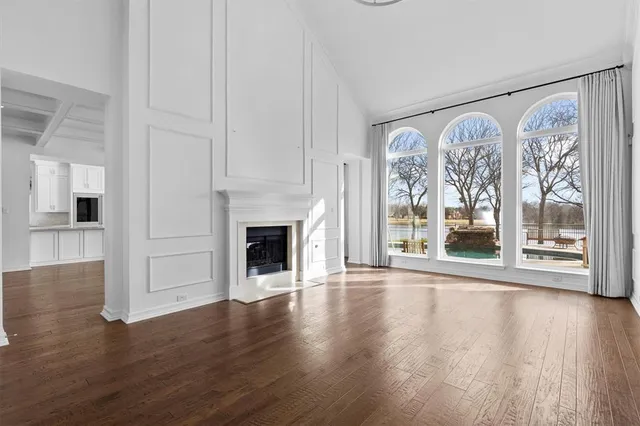 a view of an empty room with wooden floor and a fireplace