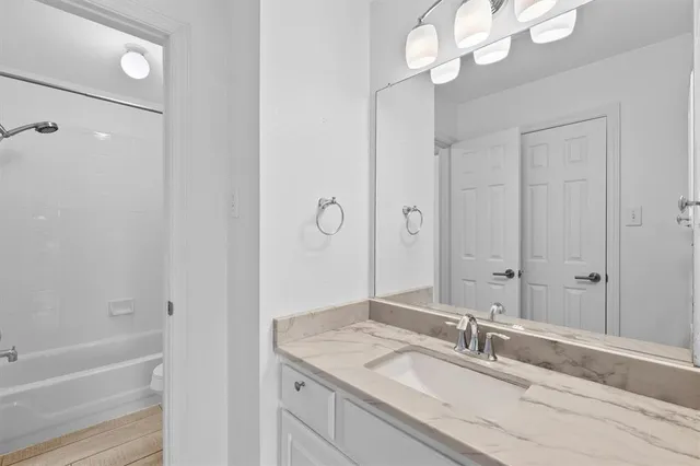 a bathroom with a granite countertop sink a mirror and a shower