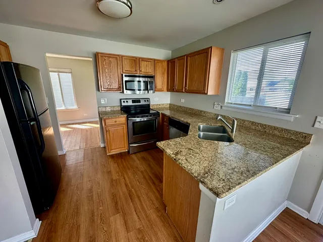 a kitchen with granite countertop a sink stove refrigerator and wooden floor