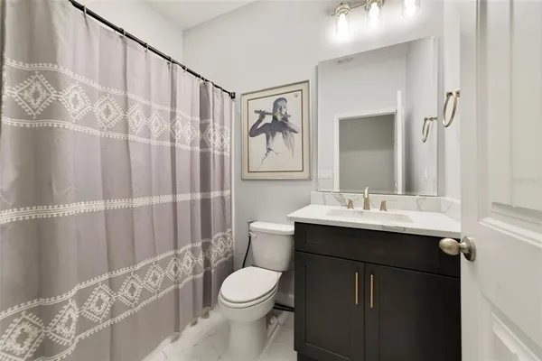 a bathroom with a sink a toilet and shower curtain