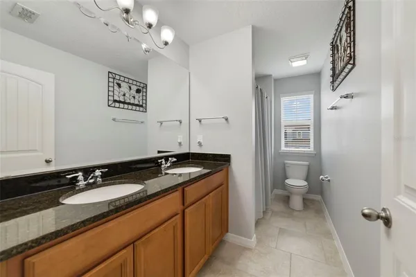 a bathroom with a granite countertop sink a mirror and a toilet