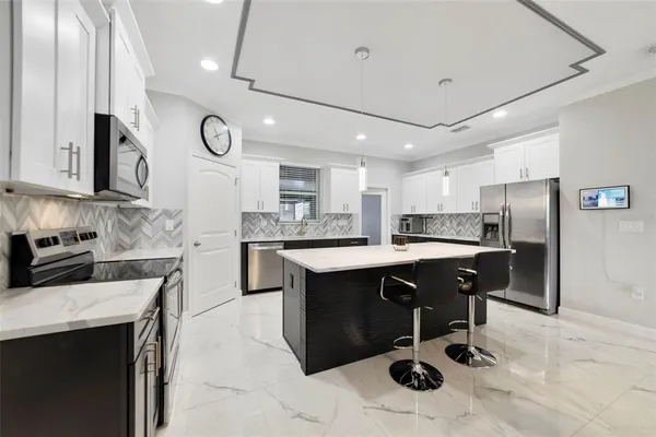 a kitchen with stainless steel appliances granite countertop a sink a stove a refrigerator and island with wooden floor