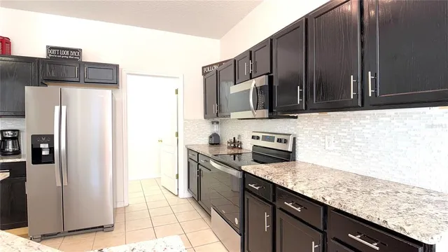 a kitchen with stainless steel appliances granite countertop a refrigerator and a stove top oven