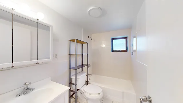 a bathroom with a bathtub shower sink mirror and toilet