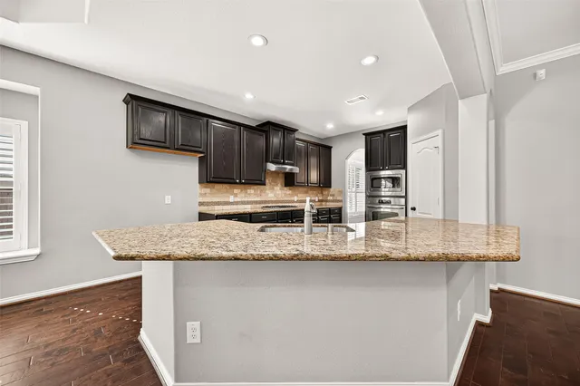 a kitchen with stainless steel appliances granite countertop a sink a stove and a refrigerator