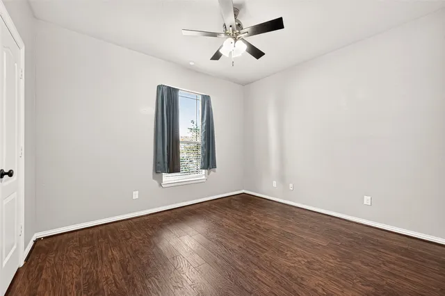 an empty room with wooden floor ceiling fan and windows