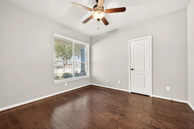 a view of an empty room with window and wooden floor