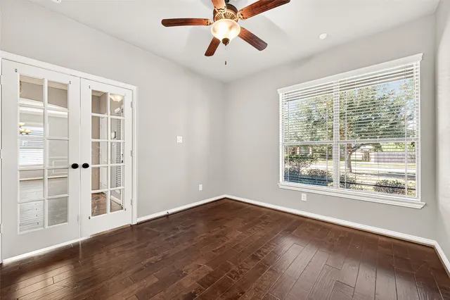 a view of an empty room with a window and wooden floor