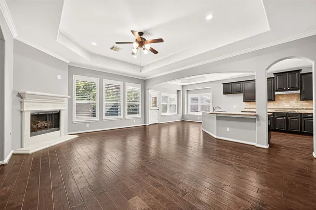 a view of an empty room with wooden floor and a kitchen