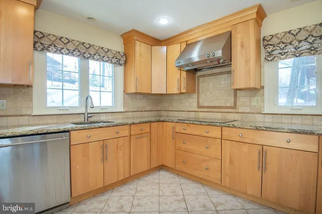 a kitchen with granite countertop white cabinets sink and window