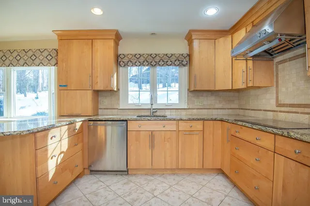 a kitchen with granite countertop a sink window and cabinets