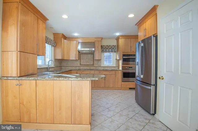 a kitchen with stainless steel appliances granite countertop a refrigerator a sink and a stove