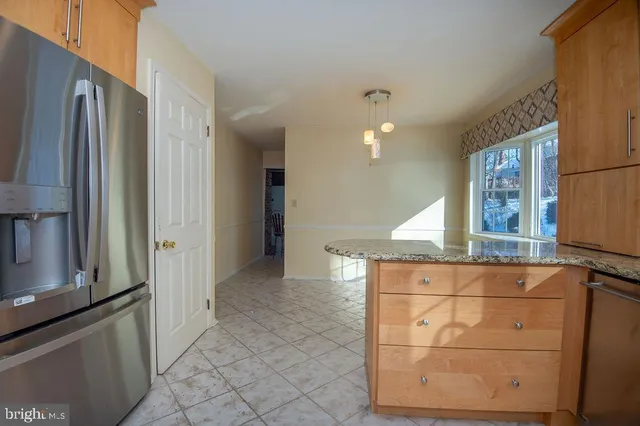 a view of a refrigerator in kitchen and an empty room