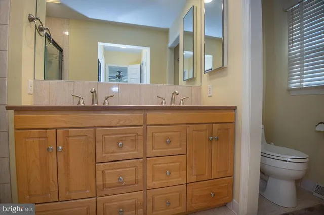 a bathroom with a granite countertop toilet sink and mirror