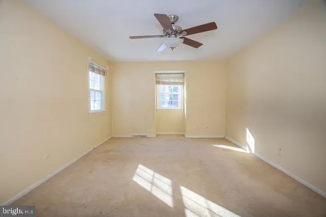 an empty room with windows and fan