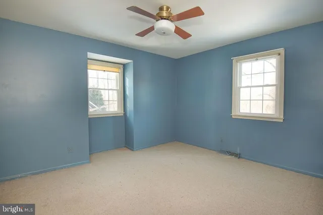 an empty room with windows and fan