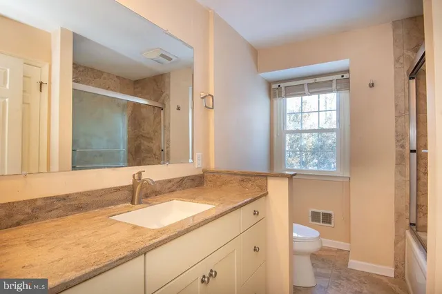 a bathroom with a granite countertop sink toilet and shower