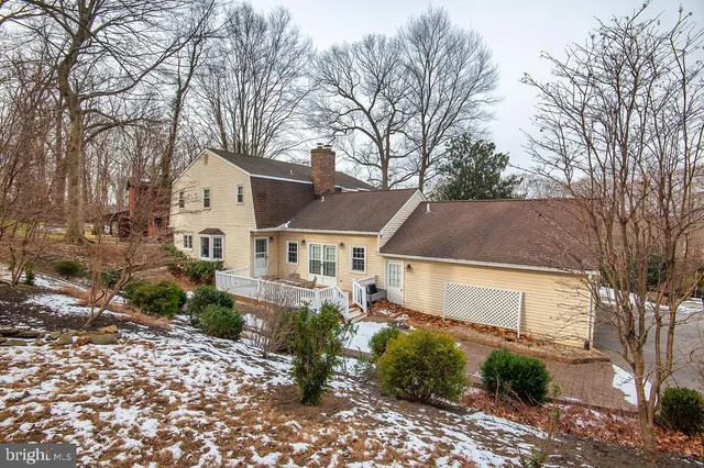a view of a white house next to a yard with a plants and trees