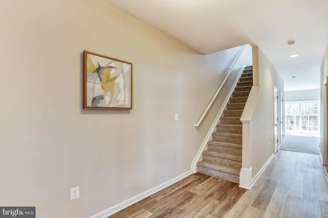 a view of an empty room with wooden floor and stairs