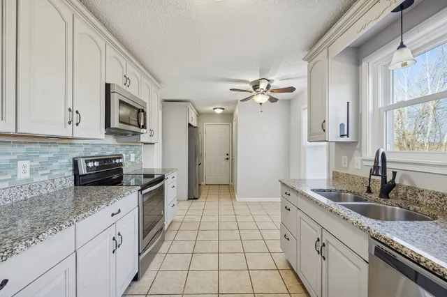 a kitchen with granite countertop a sink stove and cabinets