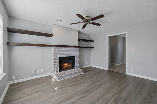 a view of a livingroom with a fireplace wooden floor and a window