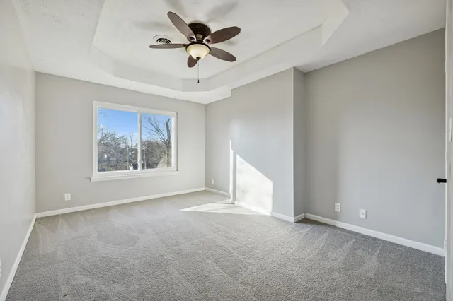 an empty room with a ceiling fan and window