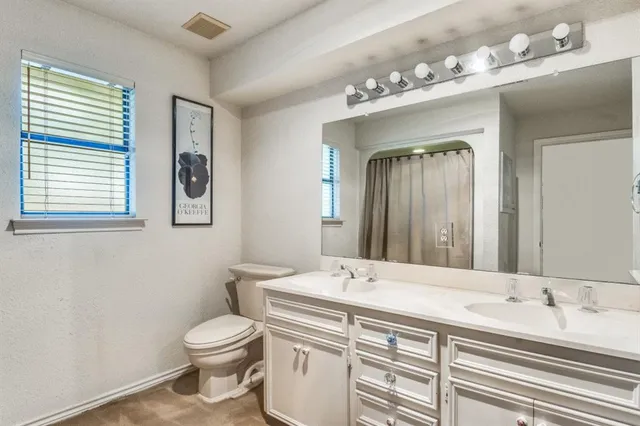 a bathroom with a double vanity sink mirror and toilet