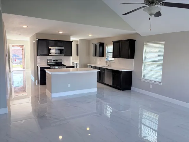 a large kitchen with stainless steel appliances a stove sink microwave and refrigerator