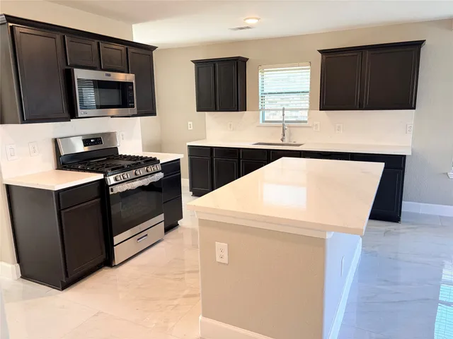 a kitchen with stainless steel appliances a stove microwave and sink