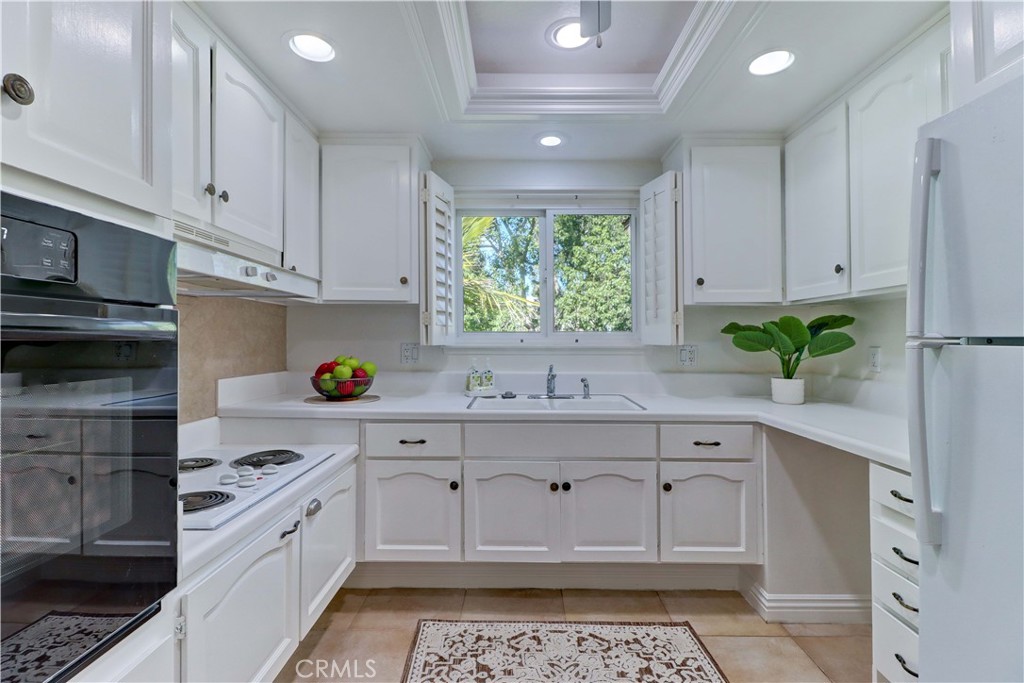 912 Ronda Sevilla, Unit O Laguna Woods, CA 92637 - Photo 17 of 55 a kitchen with kitchen island granite countertop white cabinets and white appliances