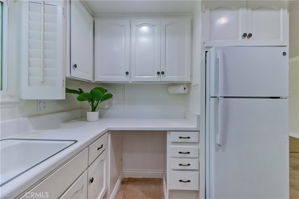 912 Ronda Sevilla, Unit O Laguna Woods, CA 92637 - Photo 21 of 55 a kitchen with stainless steel appliances white cabinets and a potted plant
