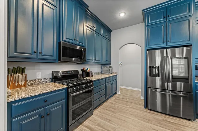 a kitchen with stainless steel appliances granite countertop a refrigerator a stove a sink and a microwave