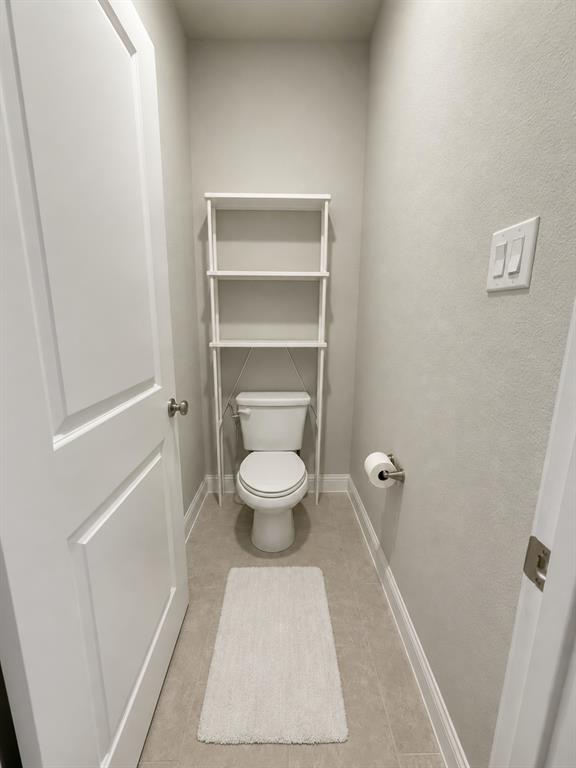 8235 Snapdragon Way Dallas, TX 75252 - Photo 17 of 29 Powder room featuring a white toilet, tile flooring, and light gray walls