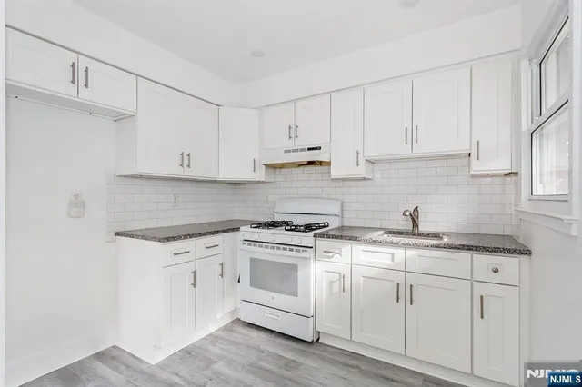 a kitchen with granite countertop white cabinets and white appliances