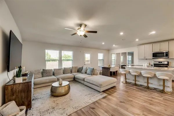 a living room with furniture a flat screen tv and kitchen view