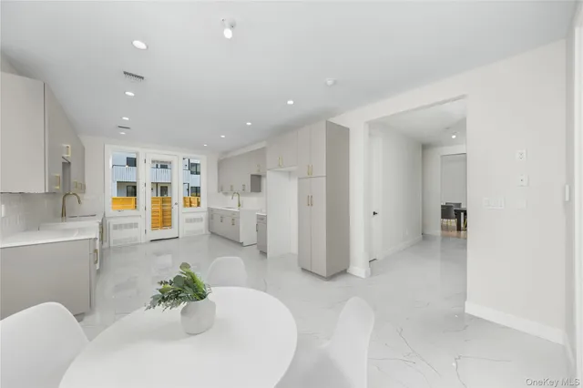 a large white kitchen with stainless steel appliances kitchen island granite countertop a refrigerator and a sink