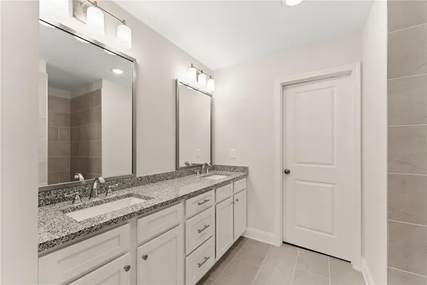 a bathroom with a granite countertop double vanity sink and mirror