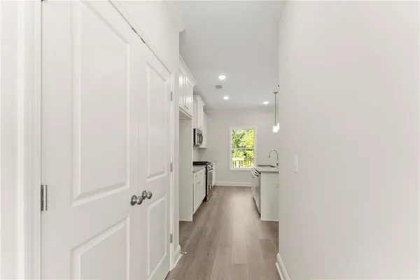 a view of a hallway with wooden floor and a bathroom