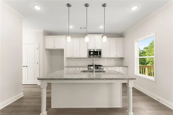 a kitchen with kitchen island granite countertop a sink a counter space appliances and cabinets
