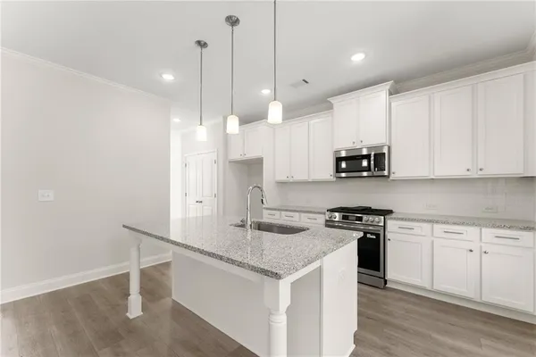 a kitchen with stainless steel appliances granite countertop a sink a stove a refrigerator and white cabinets