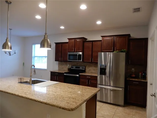 a kitchen with kitchen island granite countertop stainless steel appliances a refrigerator and a sink