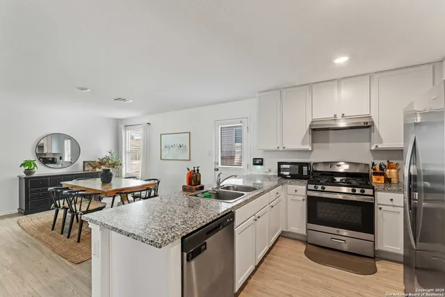 a kitchen with stainless steel appliances granite countertop a stove a sink and a refrigerator