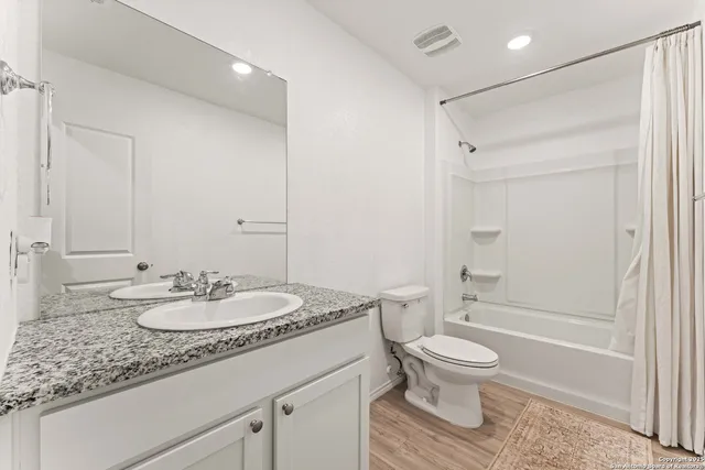 a bathroom with a granite countertop sink toilet a mirror and shower