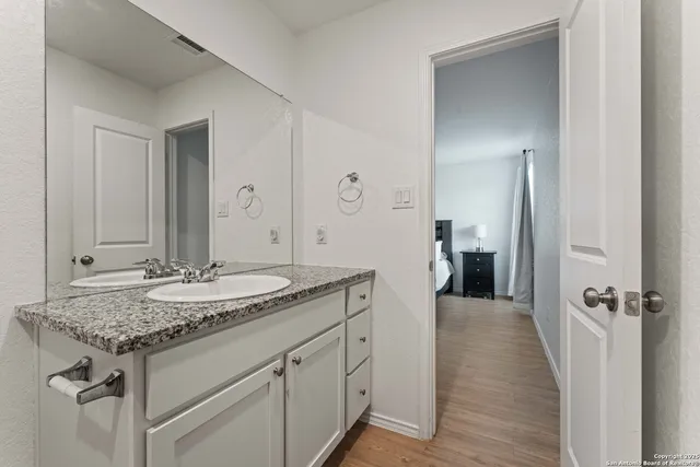 a spacious bathroom with a granite countertop sink and a mirror