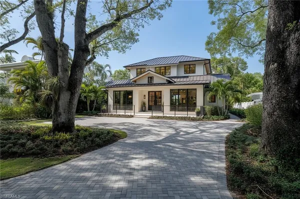 a front view of a house with garden and trees