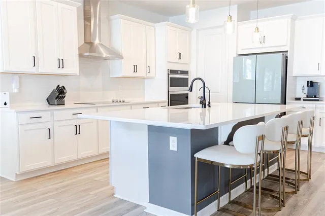 a kitchen with stainless steel appliances kitchen island a table chairs sink and cabinets