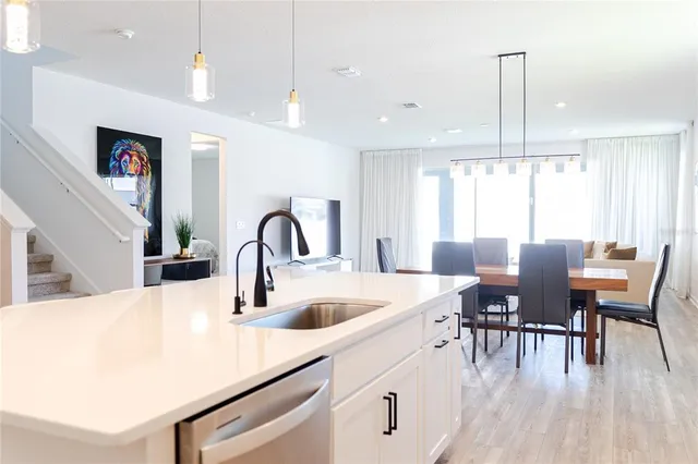 a kitchen with stainless steel appliances granite countertop a stove a sink a dining table and chairs with wooden floor