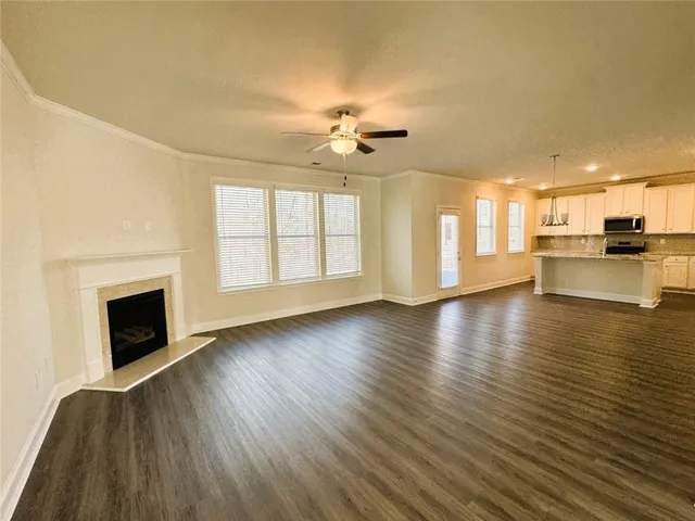 an empty room with wooden floor fireplace and windows