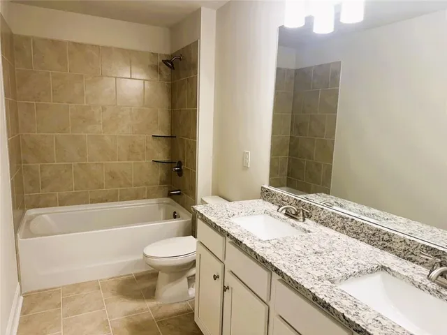 a bathroom with a granite countertop sink a toilet and bathtub