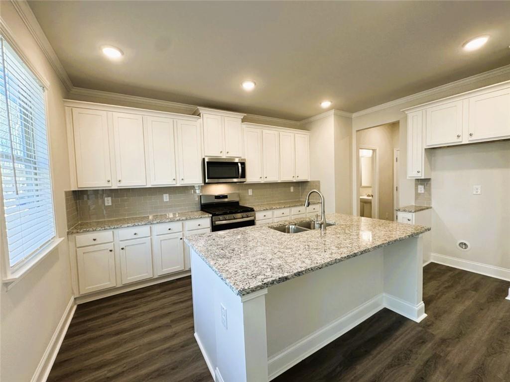 2180 Highridge Point Drive Lithia Springs, GA 30122 - Photo 8 of 24 a kitchen with granite countertop cabinets stainless steel appliances a sink and wooden floor